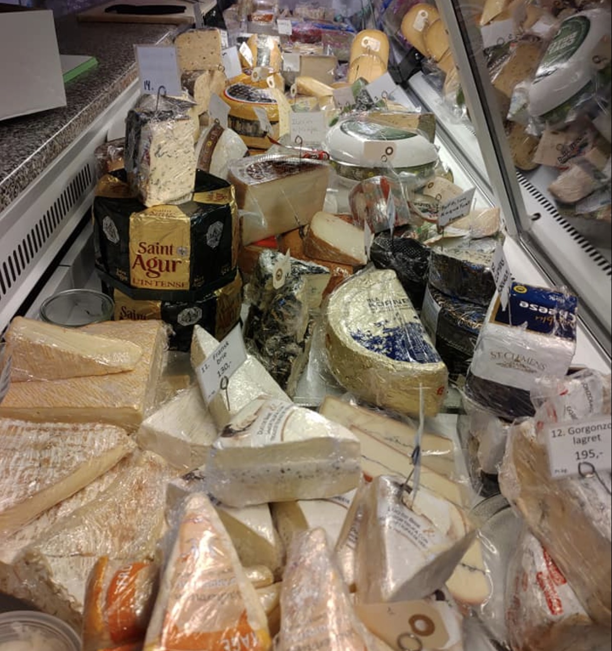 A variety of cheeses displayed in Sidinge Gårdbutik, showcasing an assortment of local and seasonal cheeses.